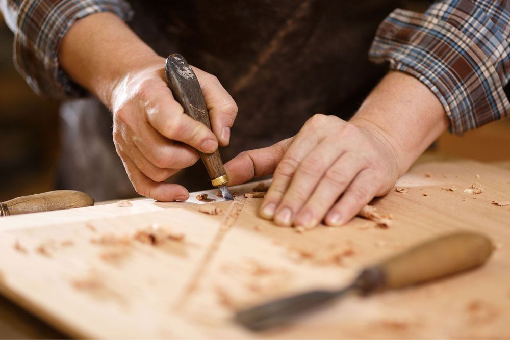 Ein Mann schnitzt an einem Stück Holz